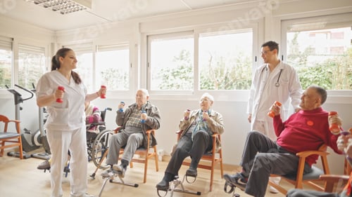 Preview: Fitness instructor leading elderly group in light dumbbell exercises indoors.