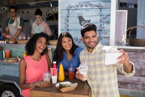 Preview: Friends taking selfie from mobile phone in food truck van