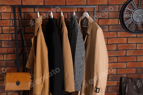 Preview: Coat rack with clothes near brick wall in hallway. Interior design