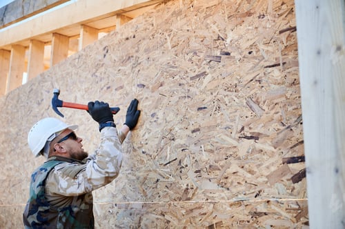 Preview: Carpenter hammering nail into OSB panel while building wooden frame house.