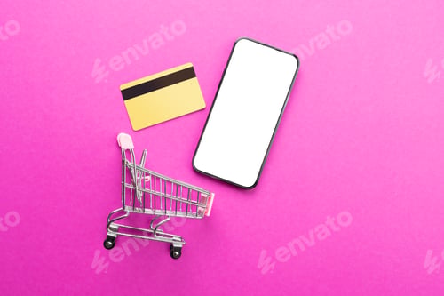 Preview: Composition of shopping cart, credit card and smartphone with copy space on pink background