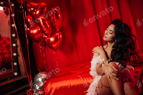Preview: Beautiful asian sexy smiling girl in undies sitting on bed posing with feather boa in red balloons