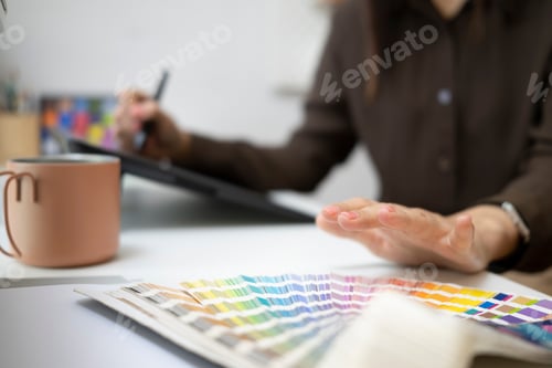 Preview: Close up view of graphic designer choosing colors from color swatch samples.