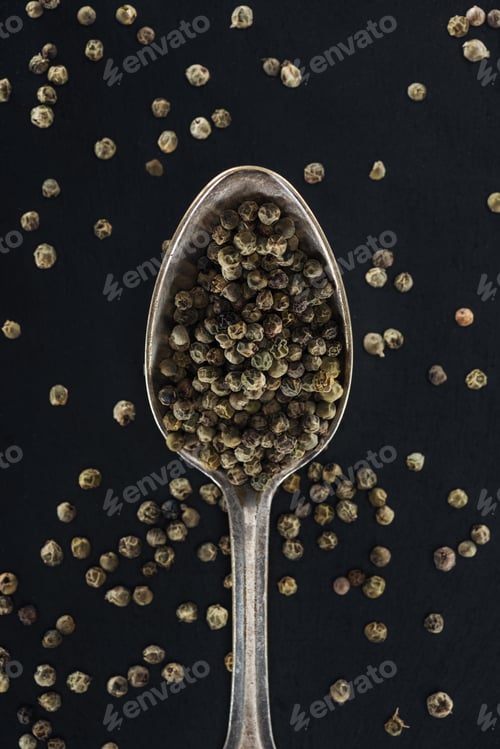 Preview: top view of pepper in silver spoon on black background