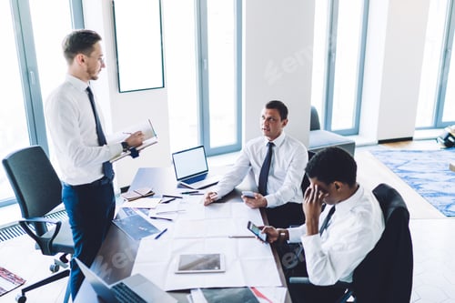 Preview: Adult businessman having discussing with multiracial coworkers during meeting in office