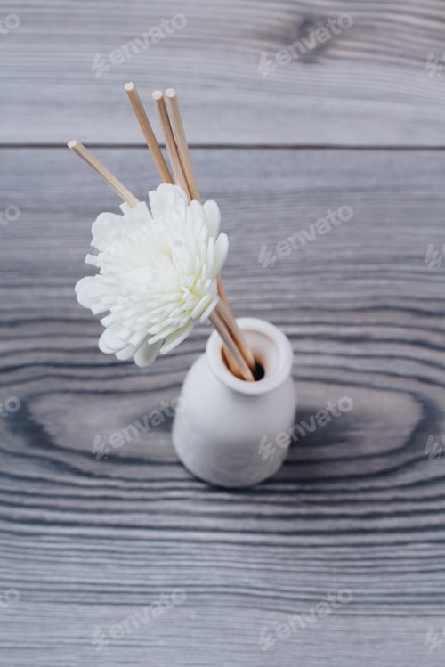 Preview: Decorative spa flower in a white vase on grey wooden background.