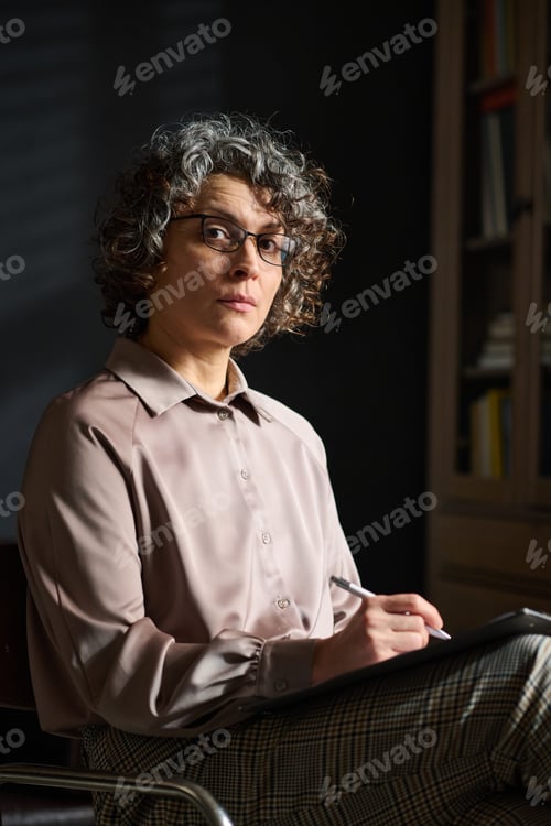 Preview: Elegant and confident mature female psychologist making notes