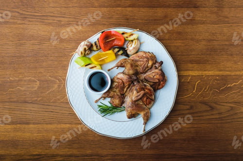 Preview: top view of roasted chickens with grilled vegetables and sauce on plate