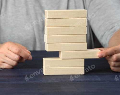 Preview: Hand pulls a wooden block out of the pile. Balance concept, situation control