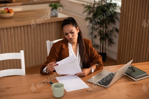 Preview: Woman Reviews Report with Scowl at Table