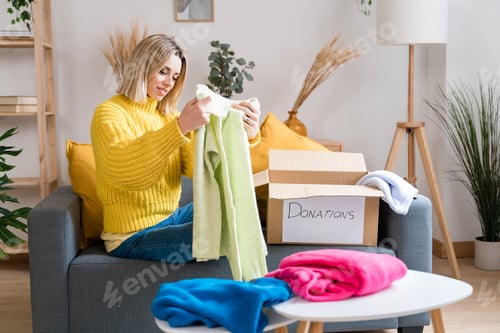 Preview: Happy woman packing clothes to donations
