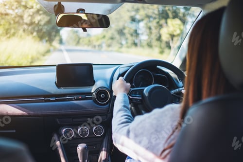 Preview: Closeup image of a woman holding steering wheel while driving a car on the road