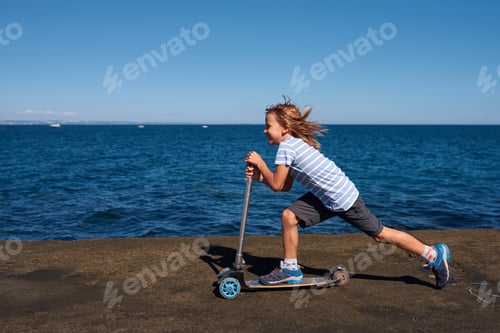 Preview: Boy riding a scooter on a pier at sunny day
