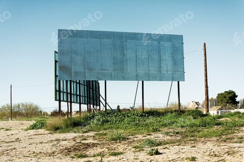 Preview: Old billboard with no posters on a lush grassy field