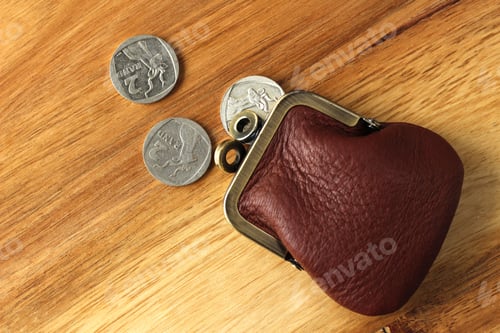 Preview: High angle shot of a leather change purse and some coins on a wooden surface