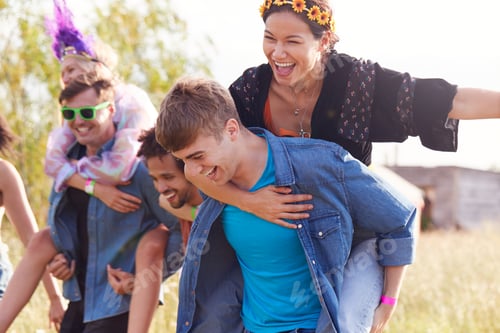 Preview: Group Of Friends Walking Back To Tent After Outdoor Music Festival With Men Giving Women Piggybacks