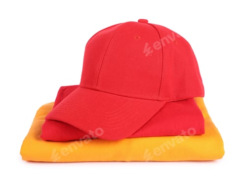 Preview: Red baseball cap and stack of folded t-shirts isolated on white. Mockup for design