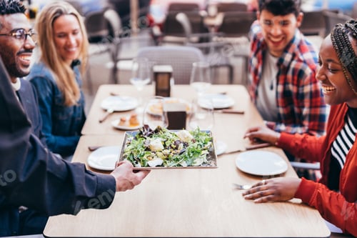 Preview: waiter serving a salad to multiethnic customers on a restaurant terrace