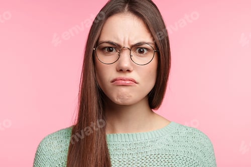 Vista previa: Aggravated brunette female with long straight dark hair, wears spectacles, frowns face in discontent