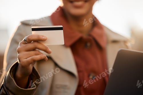 Preview: Close up of woman online shopping while using credit card and laptop.