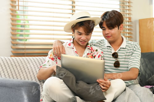 Preview: Gay male couple using laptop for searching travel destinations on website