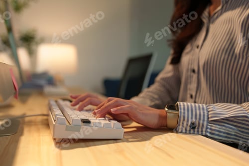 Preview: Businesswoman wearing a smartwatch, diligently typing on a sleek white keyboard in a brightly lit, m