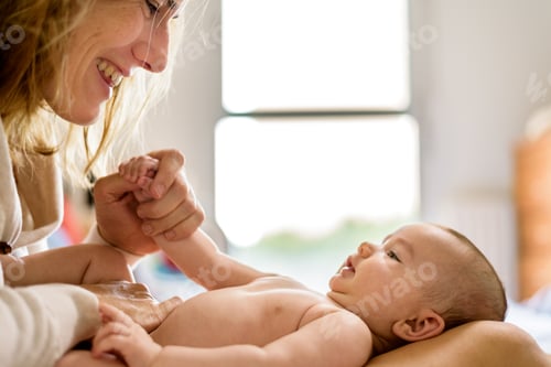 Vista previa: Bebé recién nacido posó sonriendo de manera casual sobre su madre, mirando a cámara