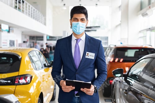 Preview: Salesman middle-eastern man in face mask posing in auto showroom