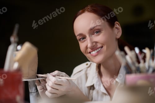 Preview: A young woman painting the pottery and looking involved