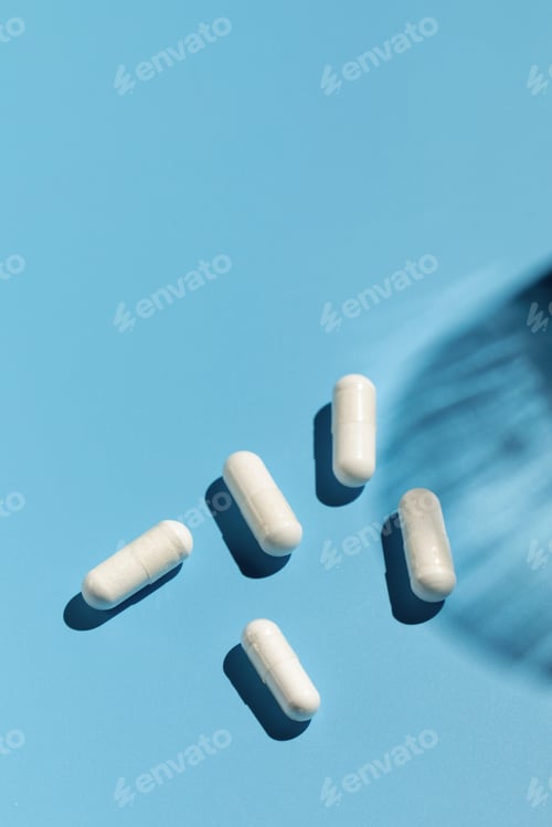 Preview: White capsules with vitamins or a dietary supplement on a blue background. Medicine, medicines