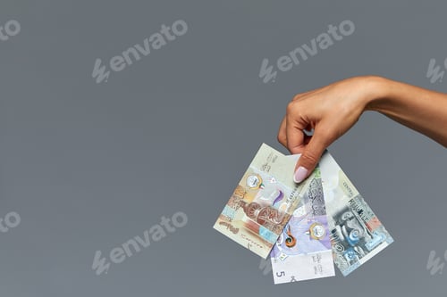 Preview: Beautiful female hands hold the Catalan rial on a gray background. Copy space, gray background