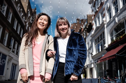 Preview: Multiracial mature women friends walking along the street with gift bags.