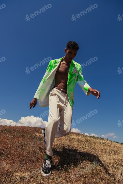 Preview: full length of trendy african american man running in field on summer day