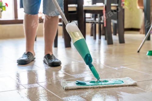 Preview: A man cleans the tiled floor in an apartment with a compact mop with a reservoir of detergent