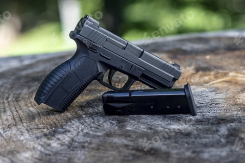 Preview: Closeup shot of the black handgun on the wood