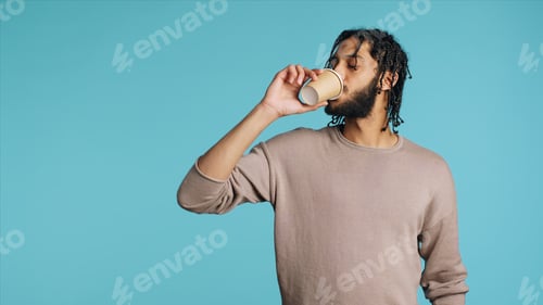 Preview: Man enjoying fresh coffee from disposable paper cup, studio background