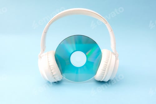 Preview: White headphones holding compact disc on light blue background, music listening and audio technology