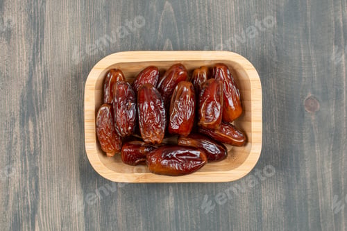 Preview: Juicy dates in a wooden plate on a wooden table