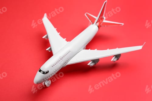 Preview: Toy airplane on red background, closeup. Travel concept