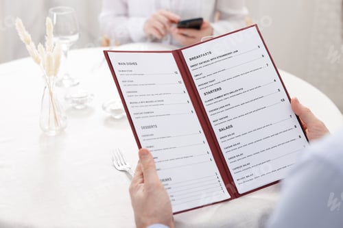 Preview: Man with menu at table in restaurant, closeup