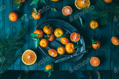Preview: Tangerines with green leaves on a green wooden table in a rustic style surrounded by spruce branches