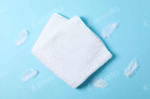 Preview: White towel and feathers on blue background, top view