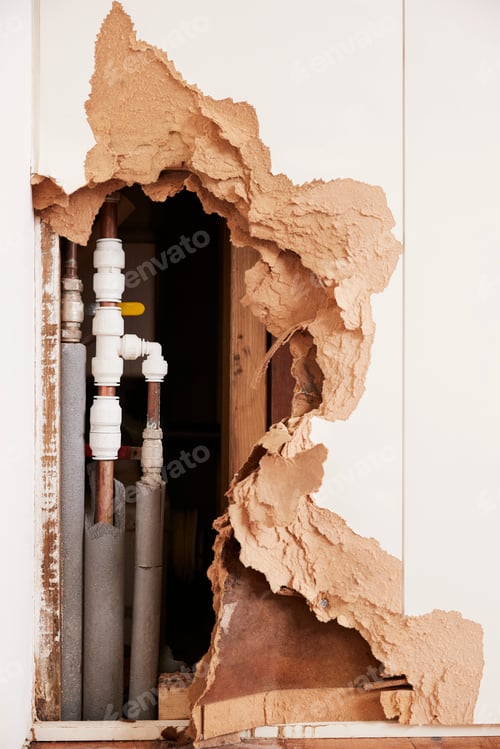 Preview: Damaged wall exposing burst water pipes after flood, vertical