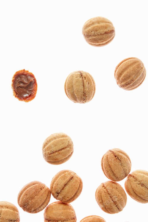 Preview: Falling cookies walnuts with milk cream on a white background