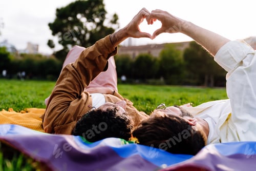 Preview: Unrecognizable gay couple on flag showing heart sign