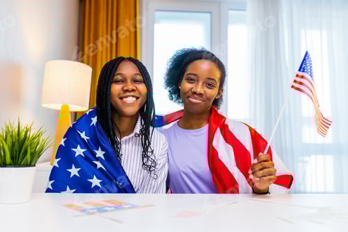 Preview: two happy african american sister celebrating usa independence day at home in cozy apartment