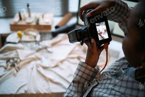 Preview: Young Adult Black Woman Photographing Product Arrangement with Digital Camera