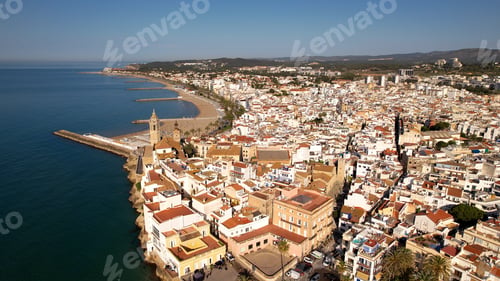 Preview: Aerial view of Sitges coastal village and Iglesia de San Bartolomé y Santa Tecla during a sunny day
