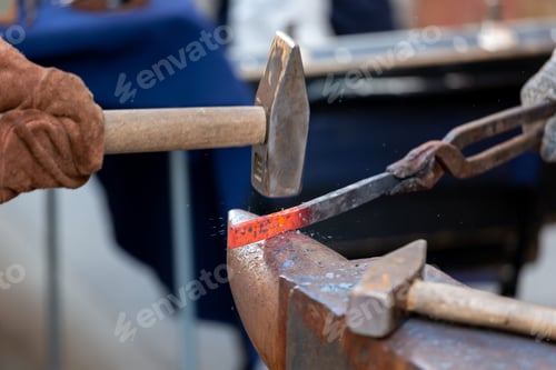 Preview: Shaping the metal. Unrecognised blacksmith forging red-hot metal with the hammer. Blacksmith concept
