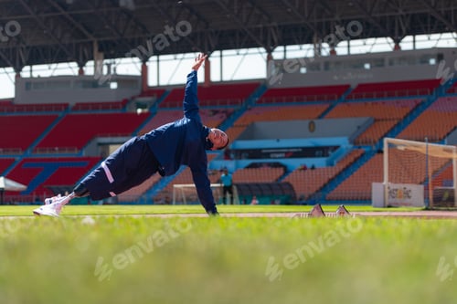 Preview: Disabled athletic man stretching and warming up before running on stadium track